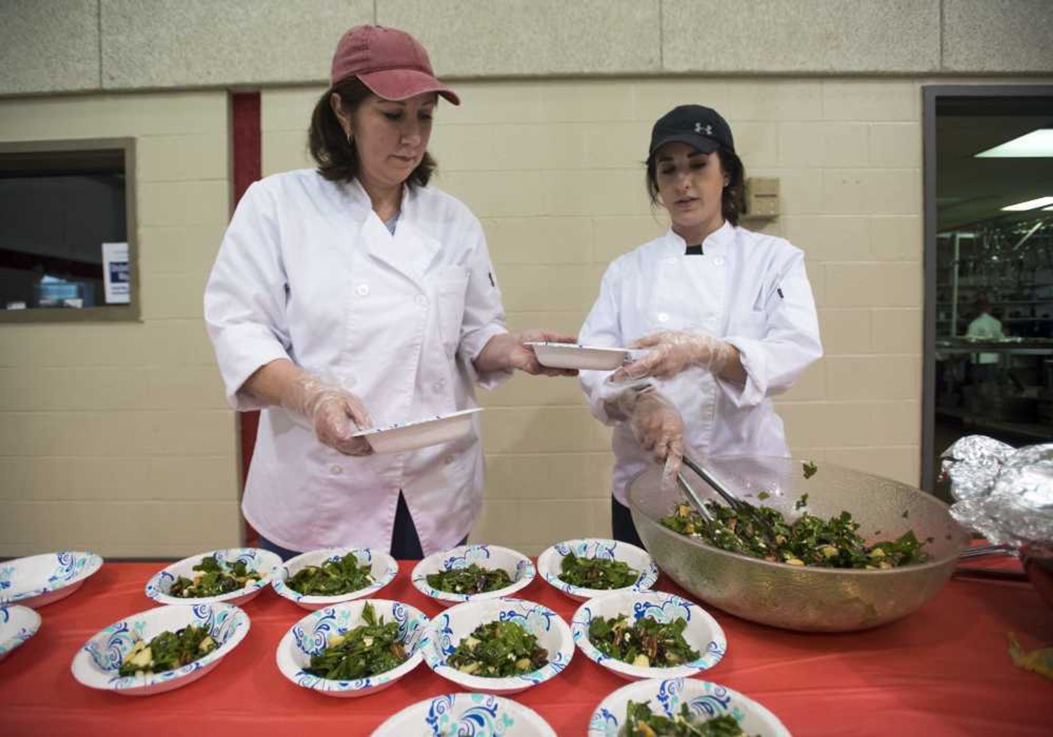 Paulla White, left, and Sarah Bower serve salads during the Empty Bowls Banquet on Sunday.